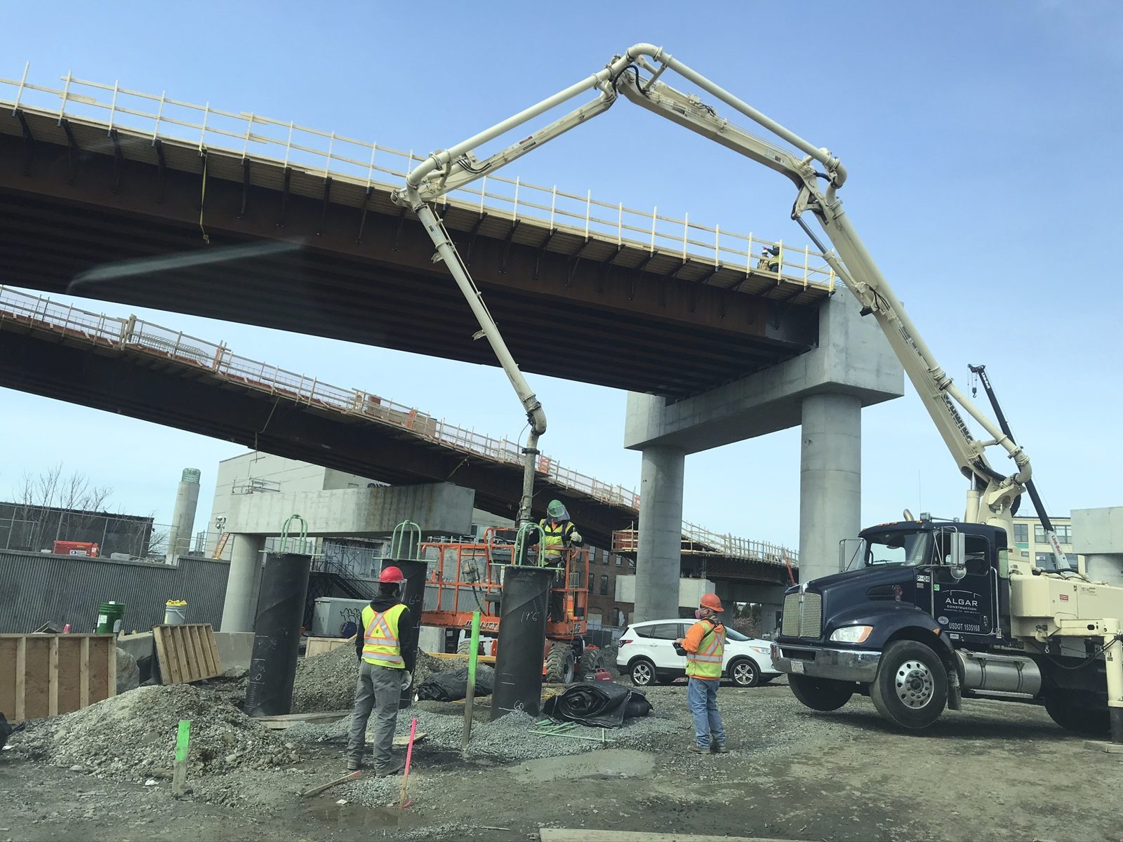Concrete pump truck pouring a foundation beneath a highway viaduct