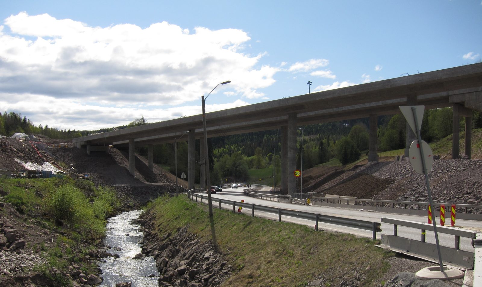 Highway overpass and roadway under construction with drainage channel