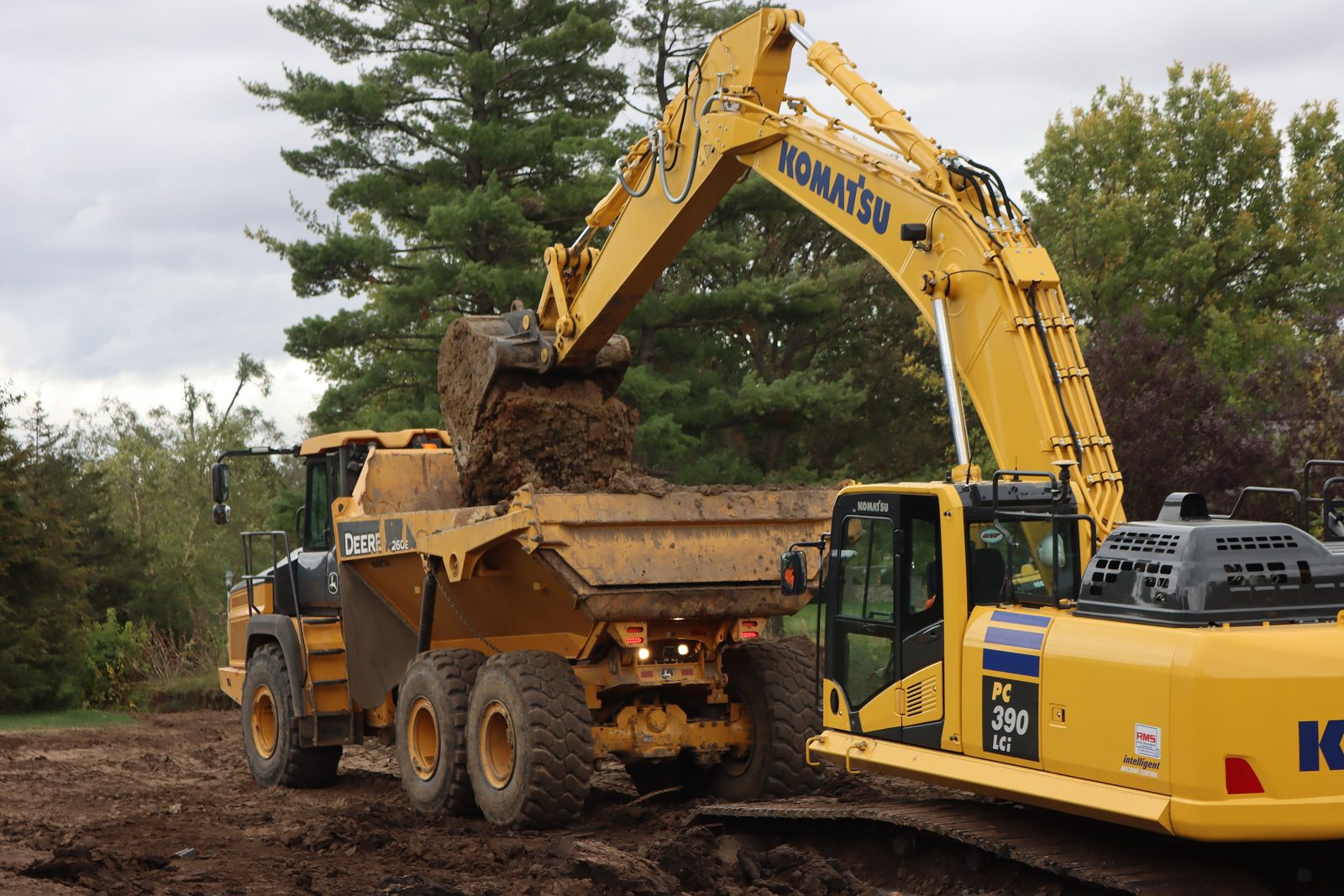 Excavator loading a dump truck during site grading and earthwork