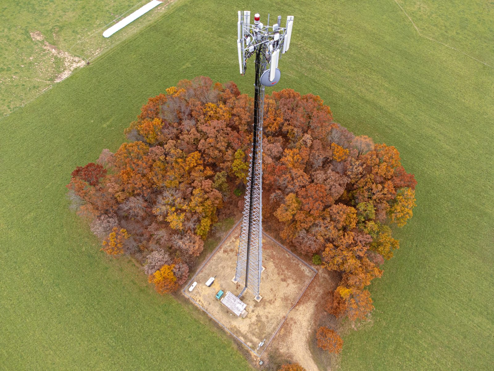 Aerial view of a lattice telecommunications tower and fenced compound